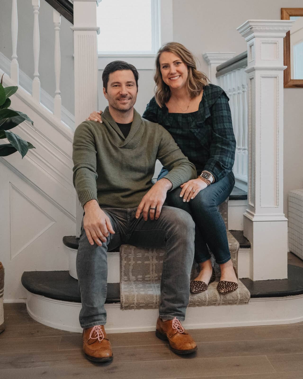 Paul and Rebecca sit on the stairs of a newly rehabbed home.