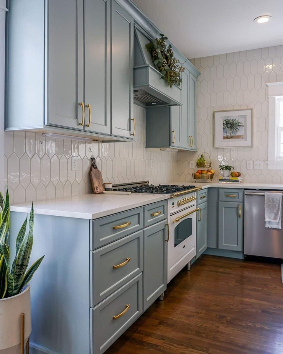 Freshly painted cabinets with gold fixtures sit against shiny white tile in a newly remodeled kitchen.